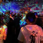 Crowd at an indoor show in Davis, with colorful projections covering the walls and ceiling